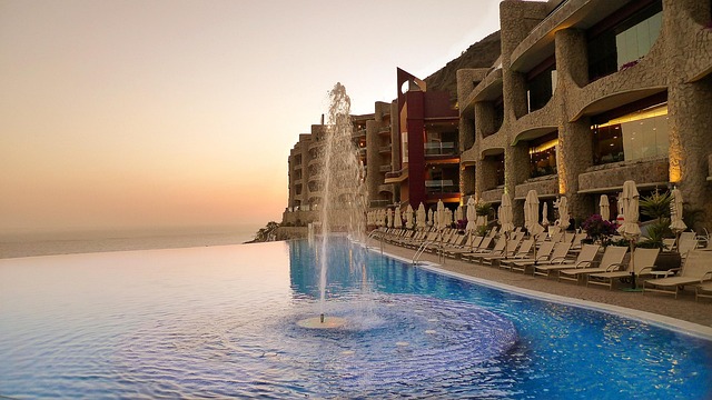 Luxury resort pool overlooking a pristine ocean at sunset, symbolizing bespoke retreats.